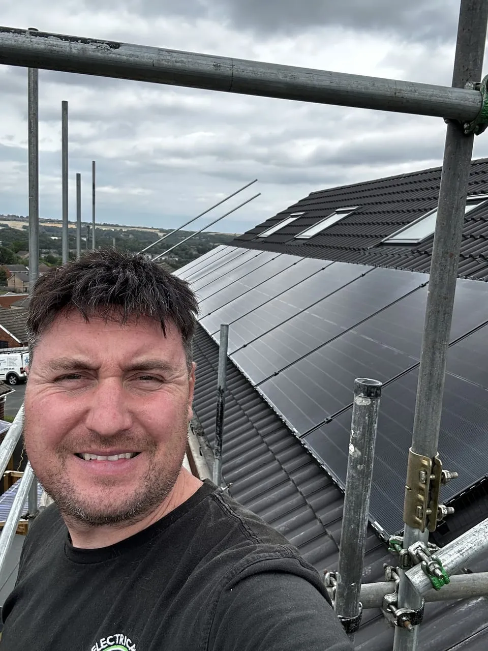 A solar installer on roof scaffolding beside a freshly fitted panel array