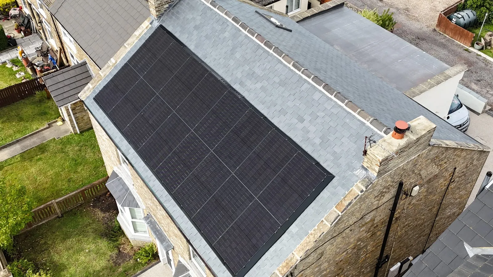 Aerial view of an all-black solar PV array on a UK stone house roof