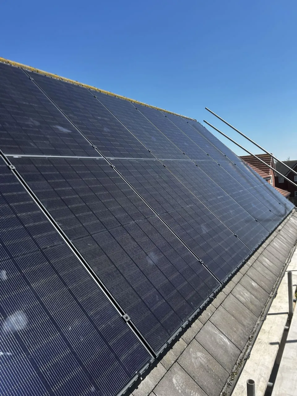 Close-up of monocrystalline solar panels on a UK roof against a clear blue sky