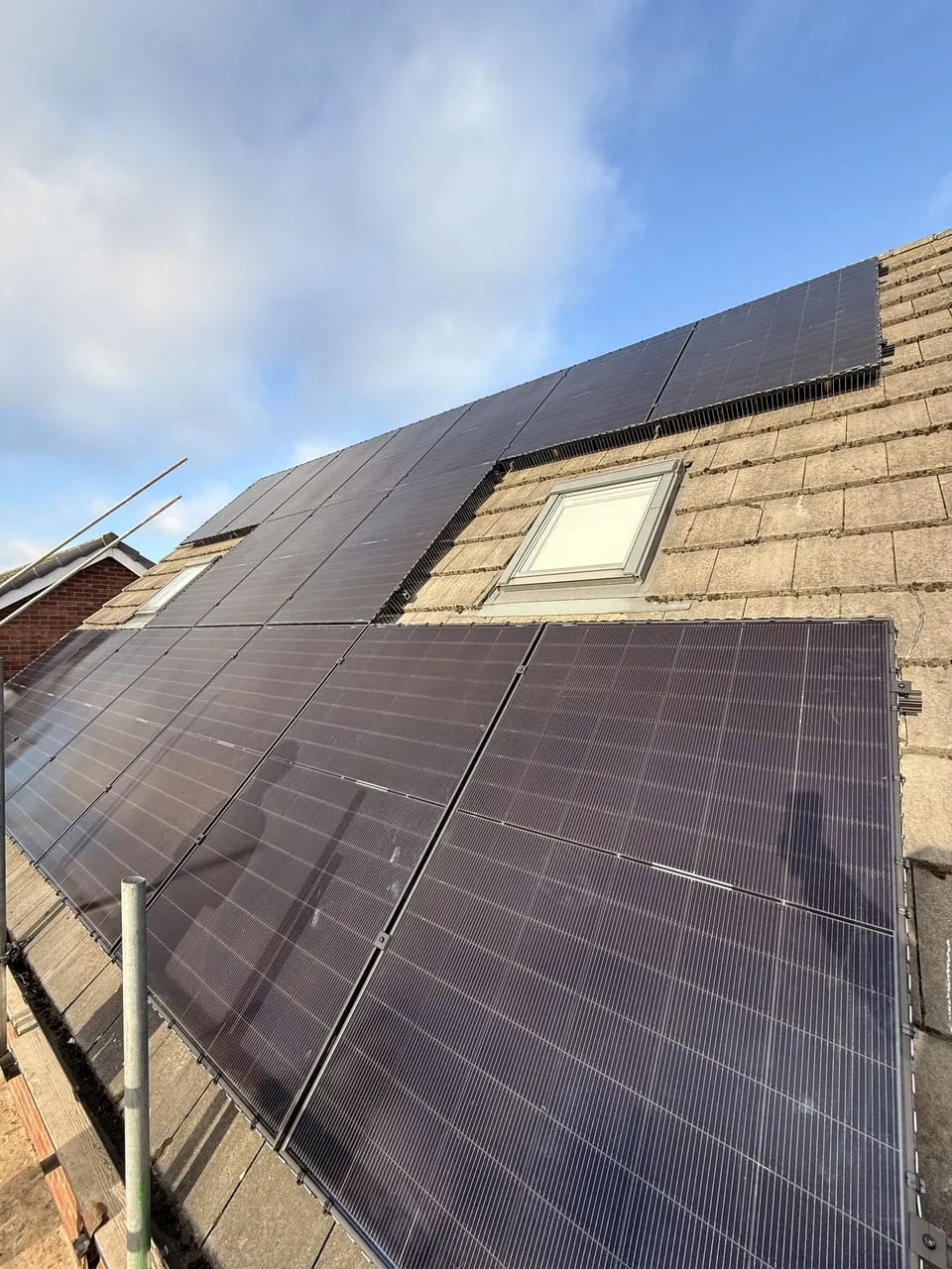 Solar panels fitted around a roof window on a UK home with blue sky